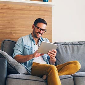 Man sitting on couch using tablet